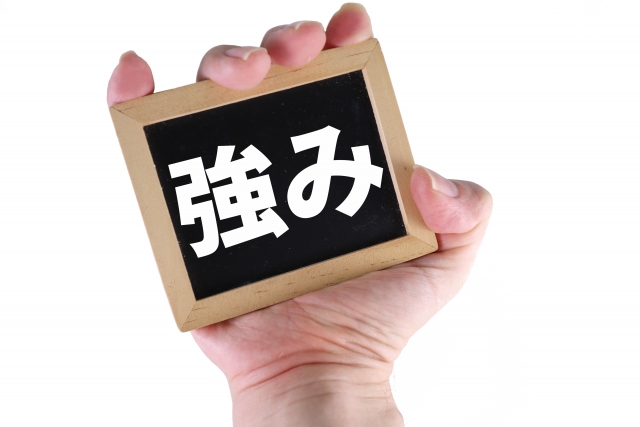 強みの文字がか書かれた板を持つ手